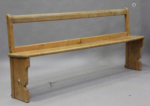 A late 19th century pine pew, the solid seat raised on shape...