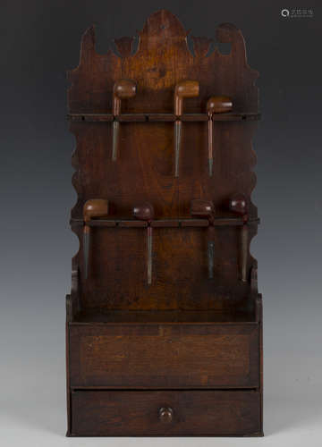 A George III provincial oak and elm wall mounted pipe rack w...