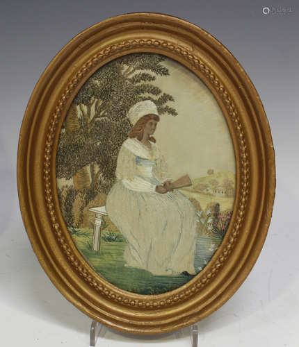 A Regency silkwork oval panel, finely worked with a lady sea...