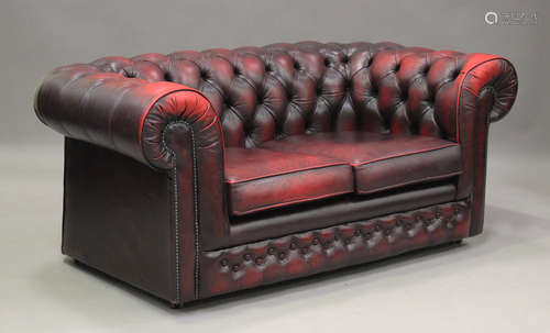 A late 20th century buttoned red leather two-seat Chesterfie...