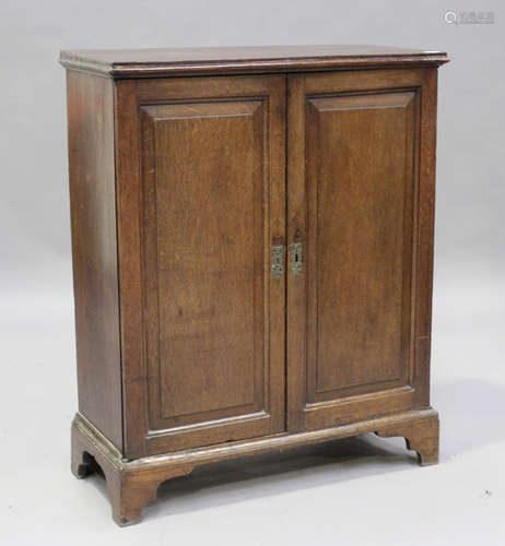 A George III oak side cabinet, fitted with a pair of panelle...