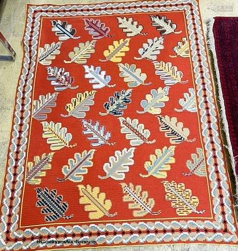 A red ground multi-coloured flat weave woollen rug with leaf...