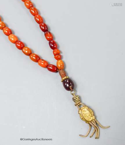 A single strand amber bead necklace, with gilt metal pendant...