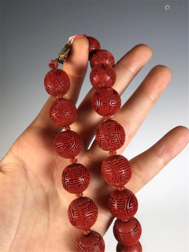 A STRING OF CARVED RED LACQUER BEADS NECKLACE