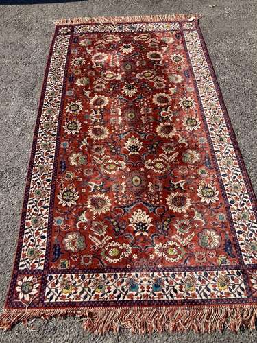 A large embroidered silk rug with a claret red ground inters...