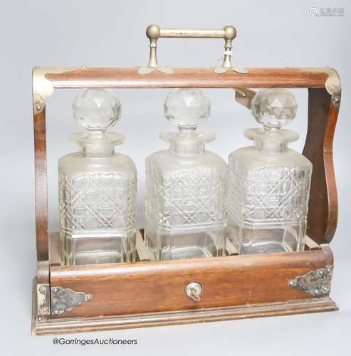 An oak three decanter tantalus, with key