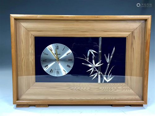 AN ELECTRONIC CLOCK WITH SILVER BAMBOO DECORATIONS