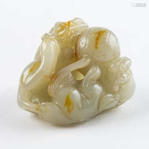 A russet and white jadeite carving of two foo dogs chasing a...