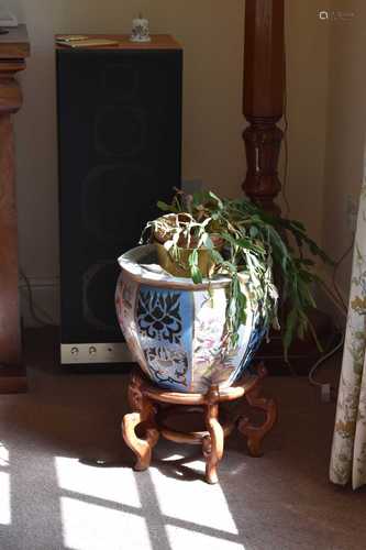 A large ceramic jardinière on a carved hardwood Chinese stan...