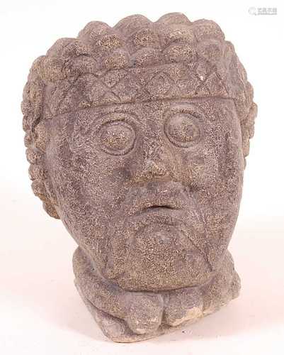 * A carved limestone male head, having stylized hair with he...