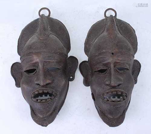 A pair of cast copper alloy wall masks, each with decorative...