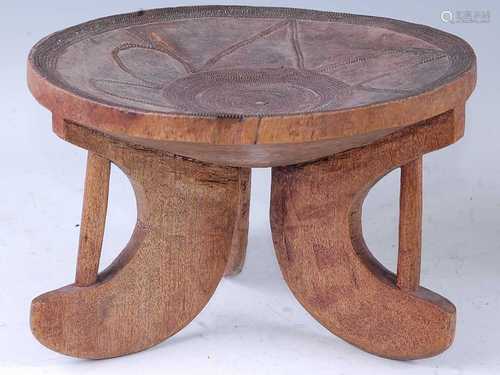 An African hardwood stool, the dished seat with copper beade...