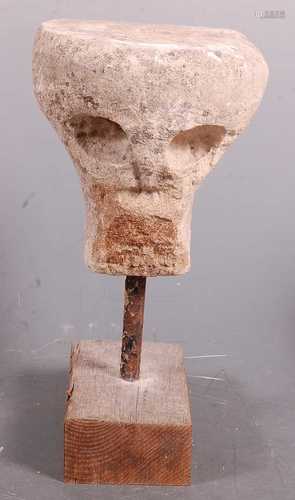 * A limestone carving in the form of a skull, mounted on a c...