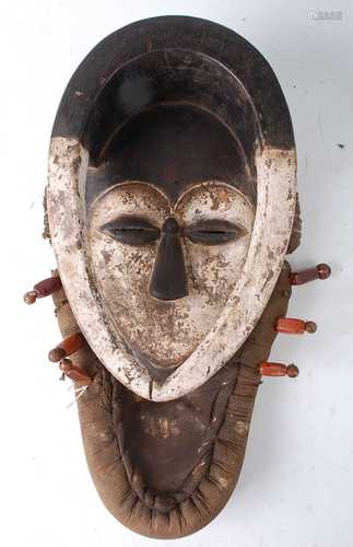 * A carved wooden ritual mask, mounted in a padded fabric su...