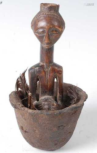 * A small carved wooden fetish figure, housed within the ori...