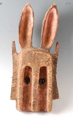 * A large carved wooden funeral mask, having elongated ears ...