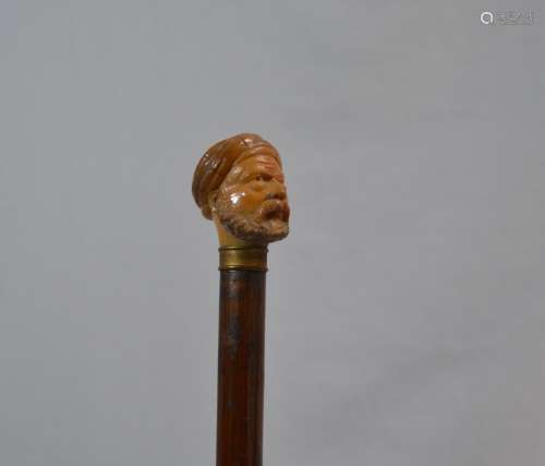 CANNE en bois, le pommeau en corne sculpté figurant une tête...