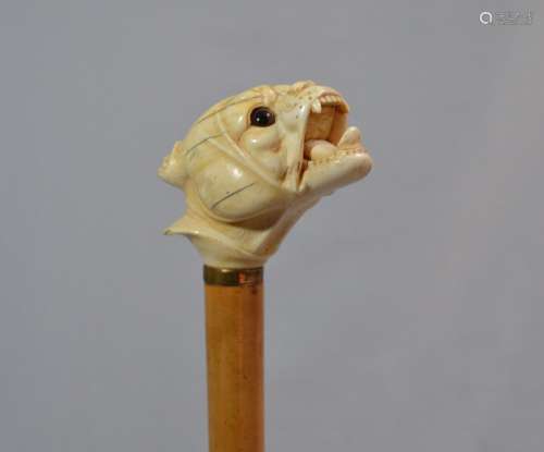 CANNE en bois, le pommeau en ivoire sculpté figurant une têt...