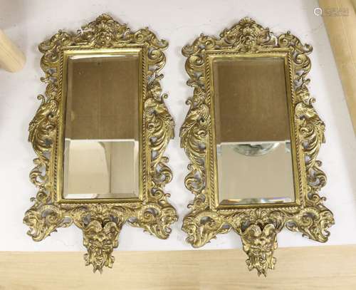 A pair of brass framed wall mirrors with devil and lion mask...