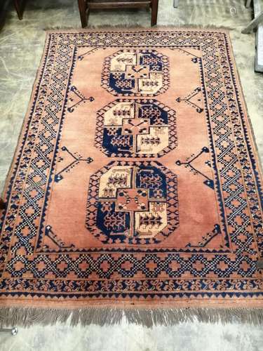 An Afghan red ground rug, woven with three central octagons,...