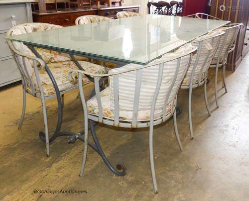 A rectangular glass topped wrought iron garden table and eig...