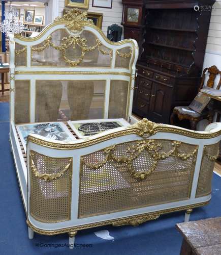 A Louis XVI style painted, giltwood and caned double bed fra...