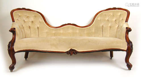 A Victorian walnut arch back settee upholstered in a beige b...