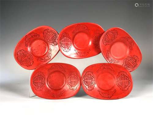 FIVE CARVED RED LACQUER INGOT SHAPED TEA SAUCERS