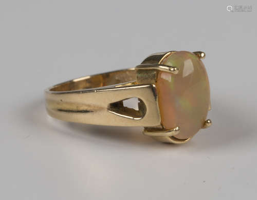 A gold ring, claw set with an oval opal, detailed '14K', wei...