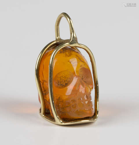 A gold mounted carved fire opal pendant, designed as a skull...