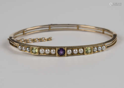 A gold, amethyst, peridot and seed pearl bangle, the front m...