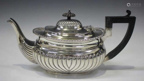 A late Victorian silver teapot of half spiral reeded cushion...