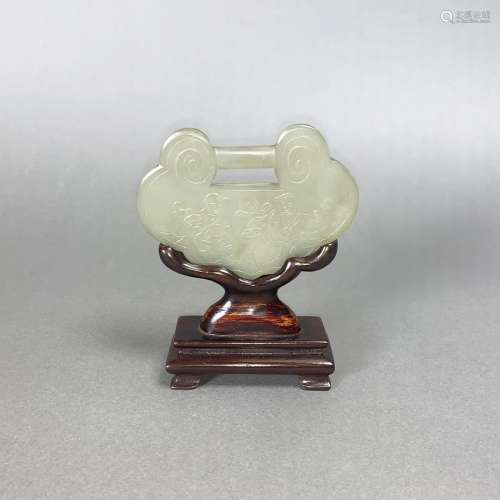 A WHITE JADE LOCK-SHAPED PLAQUE WITH WOODEN STAND