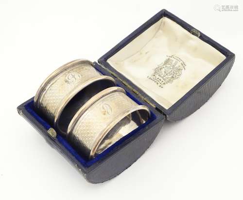 A cased pair of napkin rings of oval form with engine