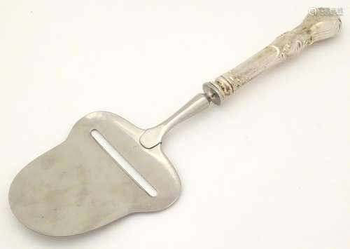 A Continental cheese plane with white metal handle.