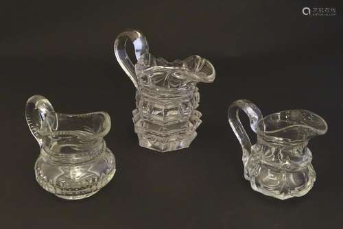 Three assorted glass cream jugs. The tallest approx 5