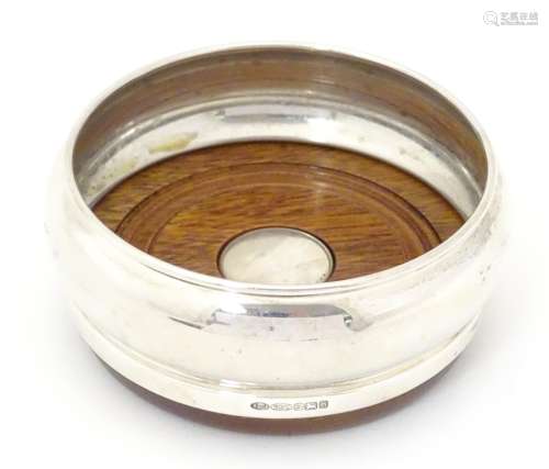A silver bottle coaster with turned wooden base,