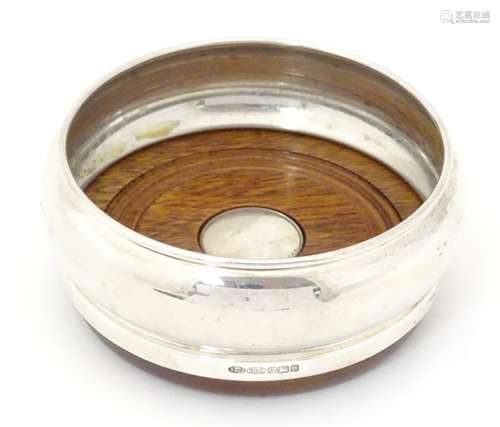 A silver bottle coaster with turned wooden base,