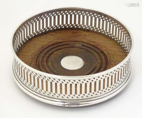 A silver bottle coaster with turned wooden base.