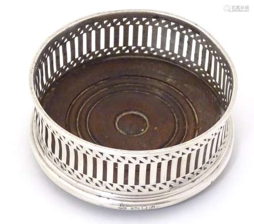 A silver bottle coaster with turned wooden base,