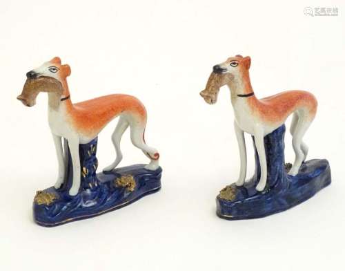 Two Staffordshire pottery greyhound dogs with hares /