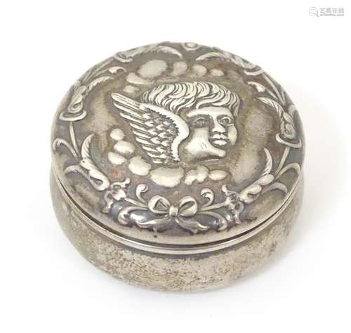 A silver pill box of circular form with embossed cherub