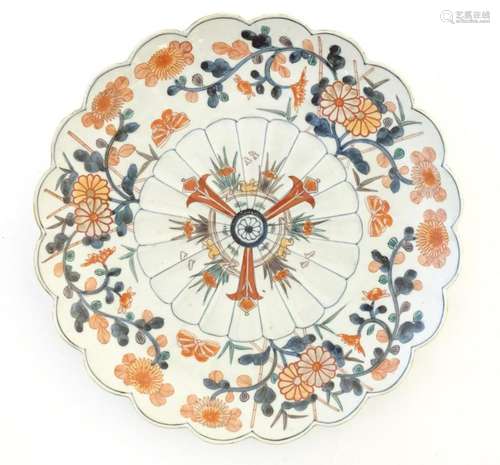 An Oriental plate with a scalloped rim decorated in the