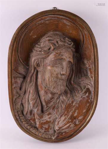 A carved oval wooden bas-relief of Jesus with a crown of tho...