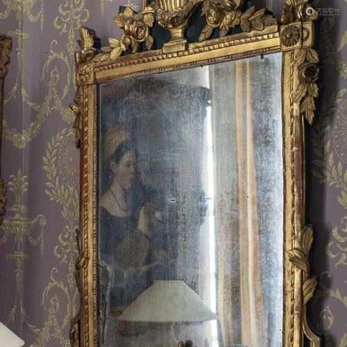 325. Miroir Louis XVI,en bois doré, orné d’une urne de fleur...