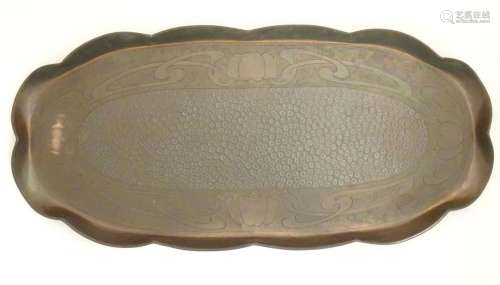An Arts an Crafts oval copper tray with a scalloped rim and ...