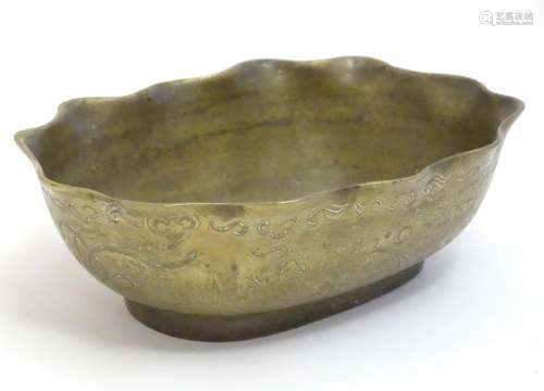 A Chinese oval brass bowl with a lobed rim, decorated with i...