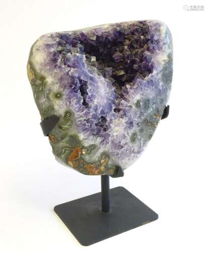 An amethyst crystal geode with polished edge. Mounted on a s...