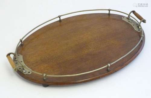 An early 20thC oak oval tray with twin handles and brass mou...