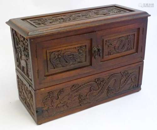 An Oriental carved hardwood box with twin doors and lift lid...